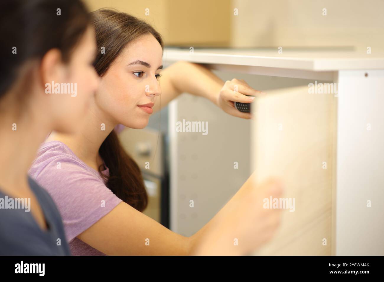 Roommates installing furniture door in the kitchen reforming house Stock Photo