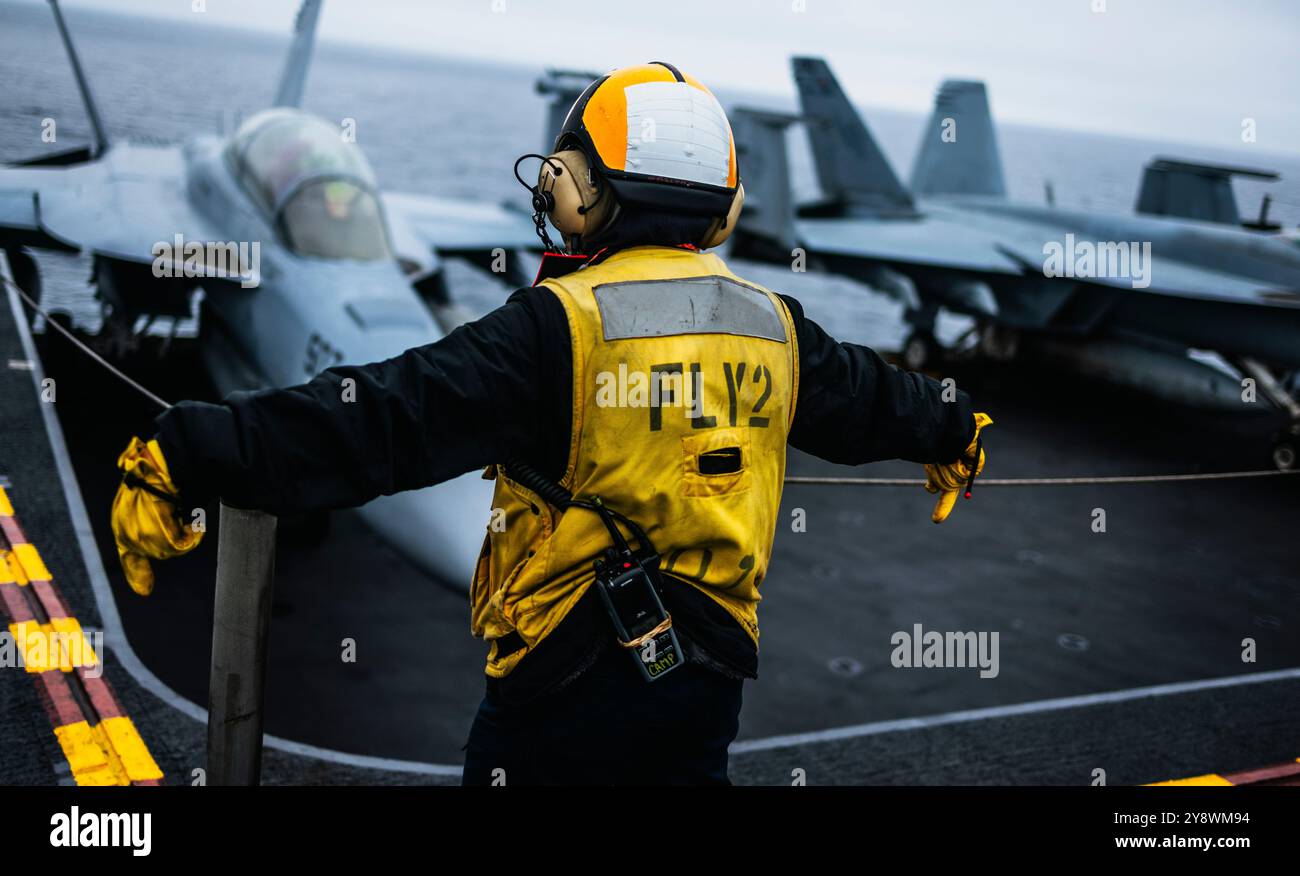 Aviation Boatswain’s Mate (Aircraft Handling) 3rd Class Angela Campuzano, from Houston, signals an aircraft elevator operator to lower the elevator on Stock Photo