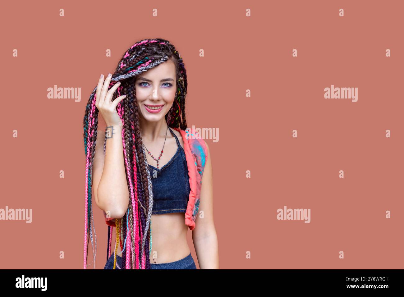 Portrait of happy young woman with braids and tattoo smiling on camera outdoor Stock Photo