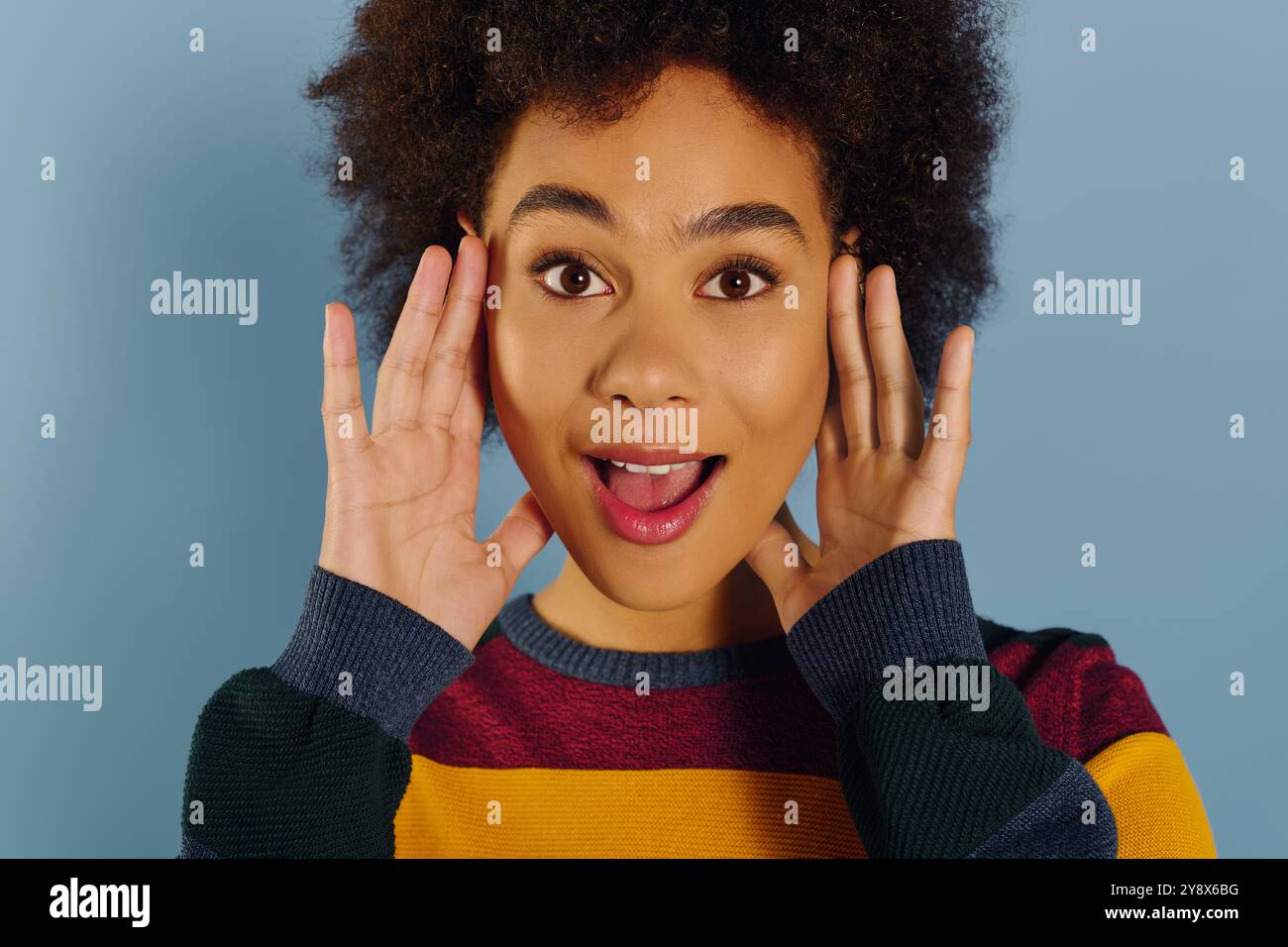 A young woman displays a surprised and joyful expression, showing her ...