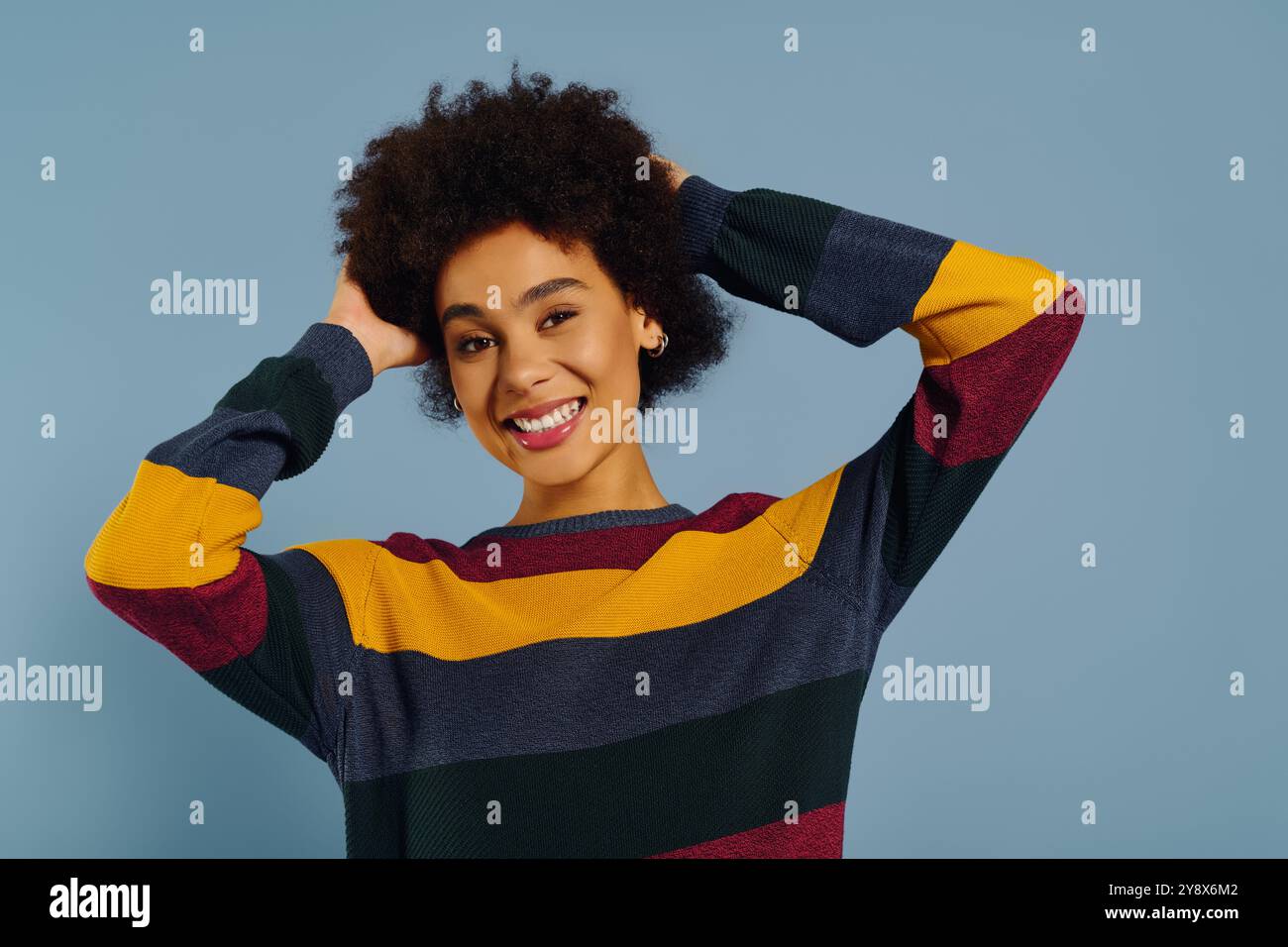 A young woman with curly hair joyfully poses, displaying her vibrant ...