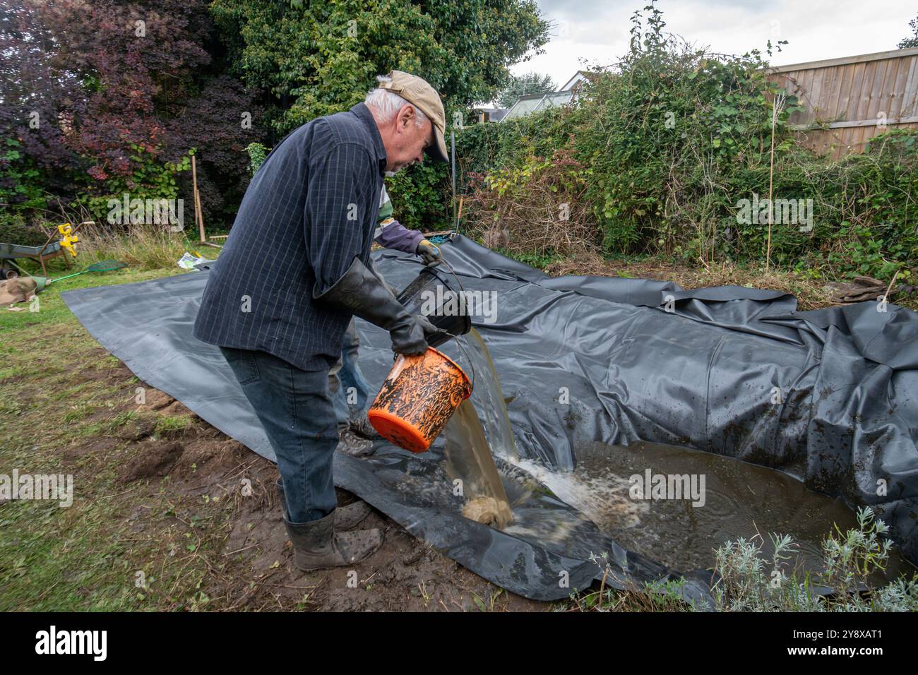 Creating and lining a wildlife pond in a garden, UK. Filling with pond