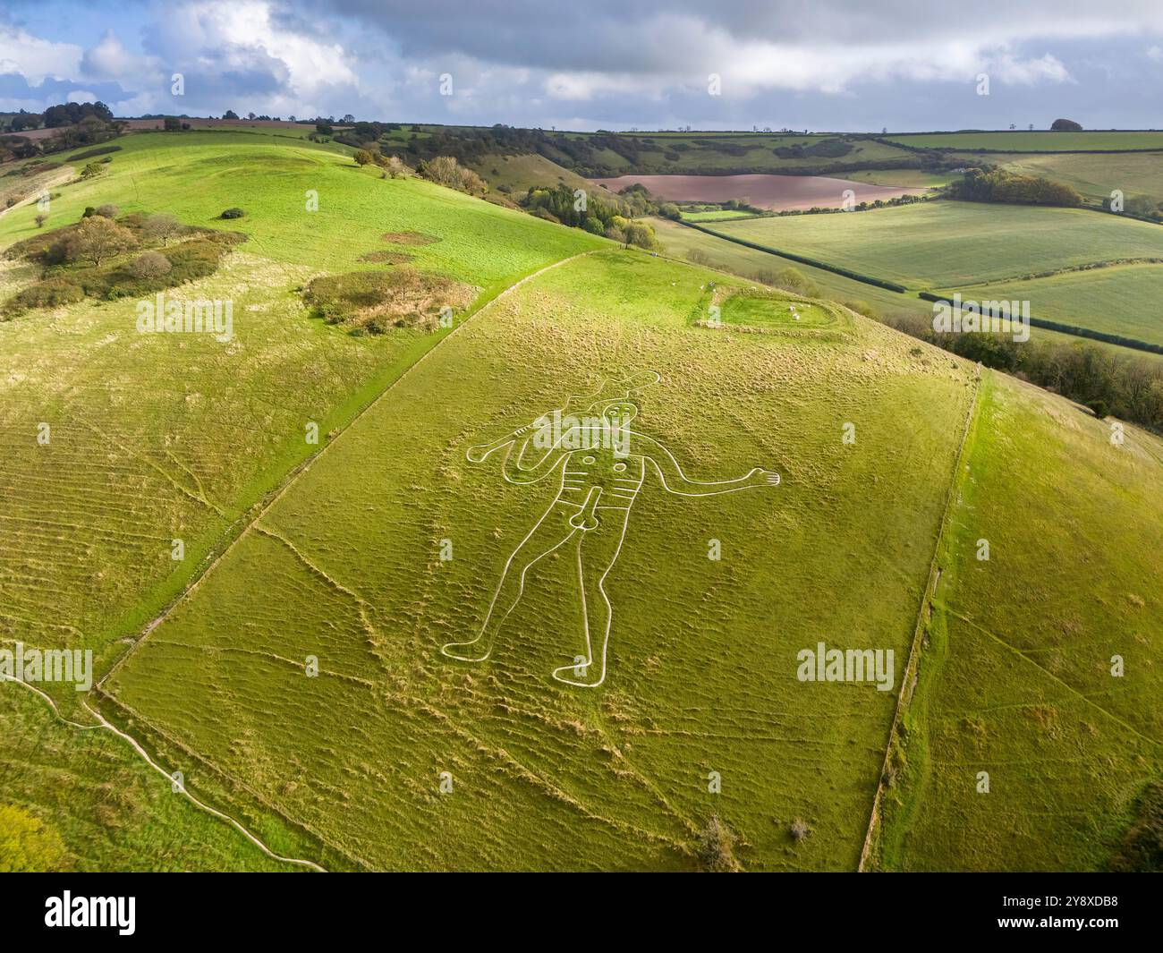 Cerne Abbas, Dorset, UK.  7th October 2024.  UK Weather.  Autumnal view from the air of the Cerne Abbas Giant at Cerne Abbas in Dorset as sunlight briefly breaks through the clouds on warm and mostly overcast morning.  Picture Credit: Graham Hunt/Alamy Live News Stock Photo