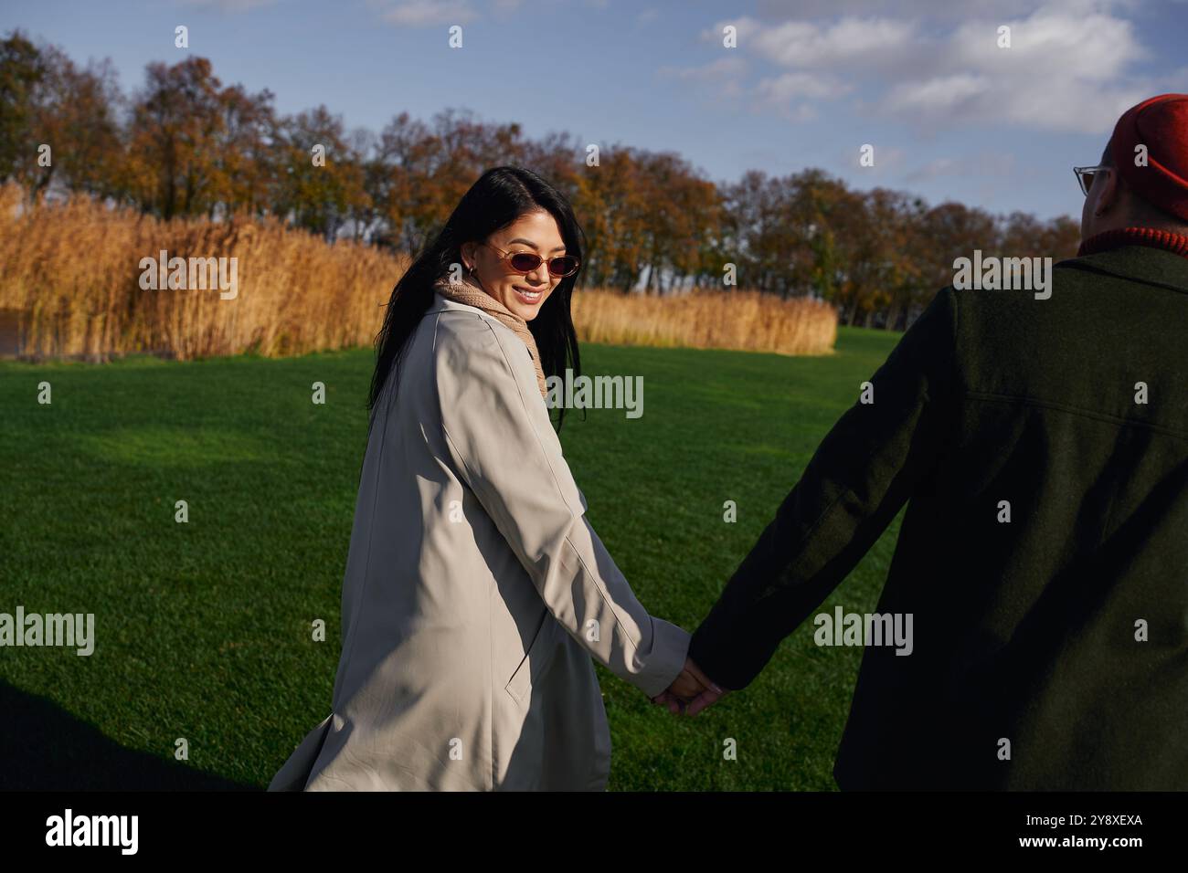 A loving couple walks hand in hand through a park, enjoying a sunny ...