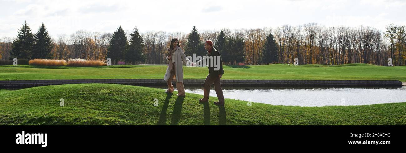 A loving couple walks hand in hand along a lush green lakeside, wrapped ...