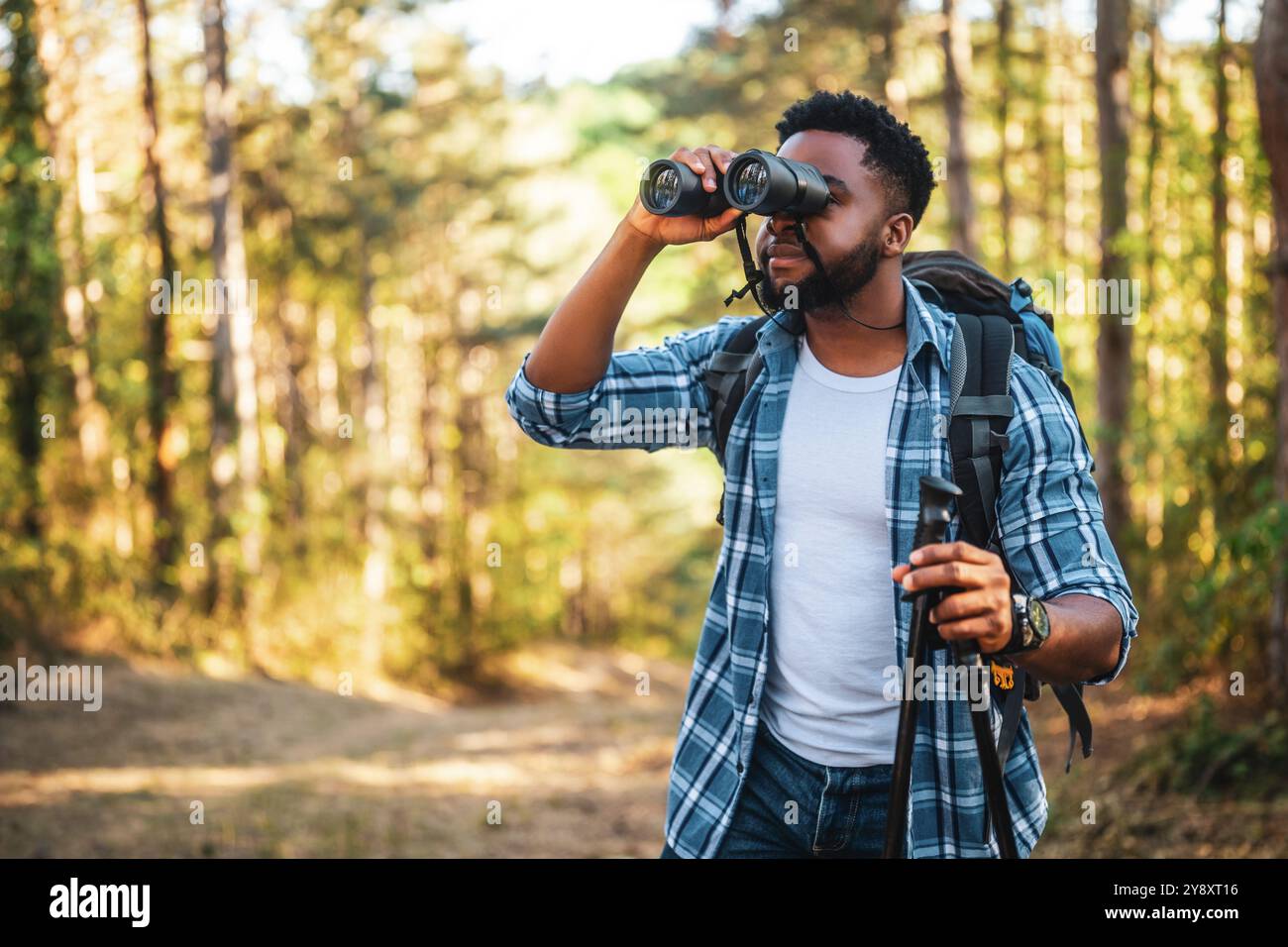Young man enjoys using binoculars and hiking in nature. Stock Photo