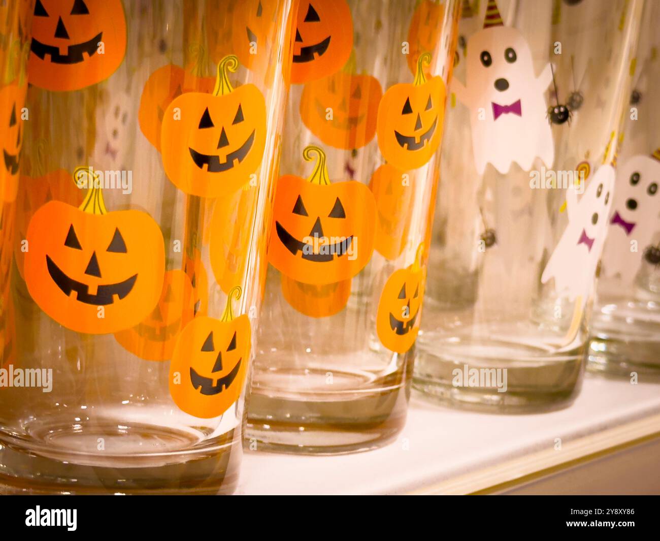 Halloween themed drinking glasses printed with pumpkin and ghost designs. October 2024: Phillip Roberts - Smartphone Captured Stock Image
