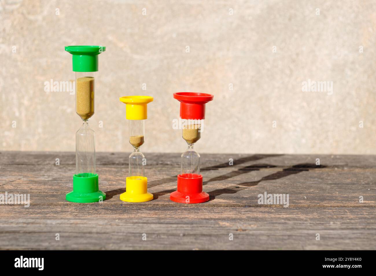 Three hourglasses on rustic weathered wooden table. Time is running Stock Photo