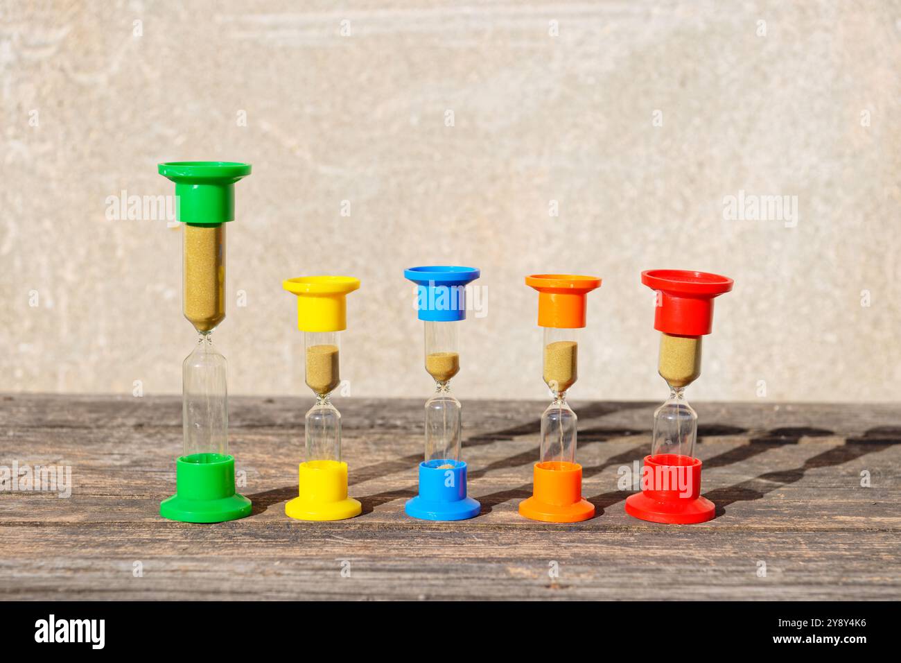 Three hourglasses on rustic weathered wooden table. Time is running Stock Photo