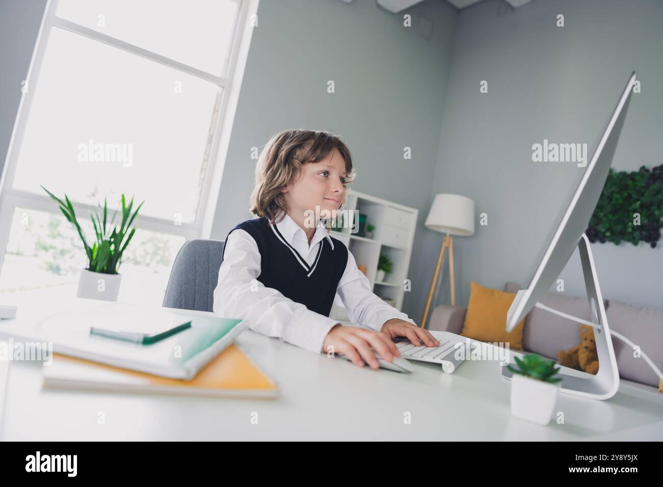 Portrait of cute charming learner boy sitting chair desktop use ...