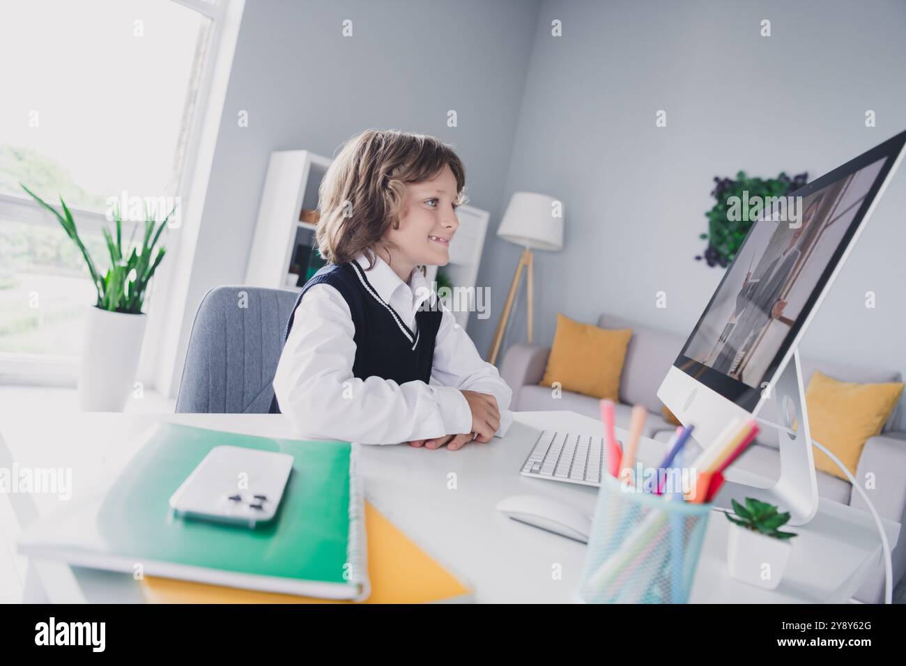 Portrait of nice cheerful learner boy sitting chair desktop use ...