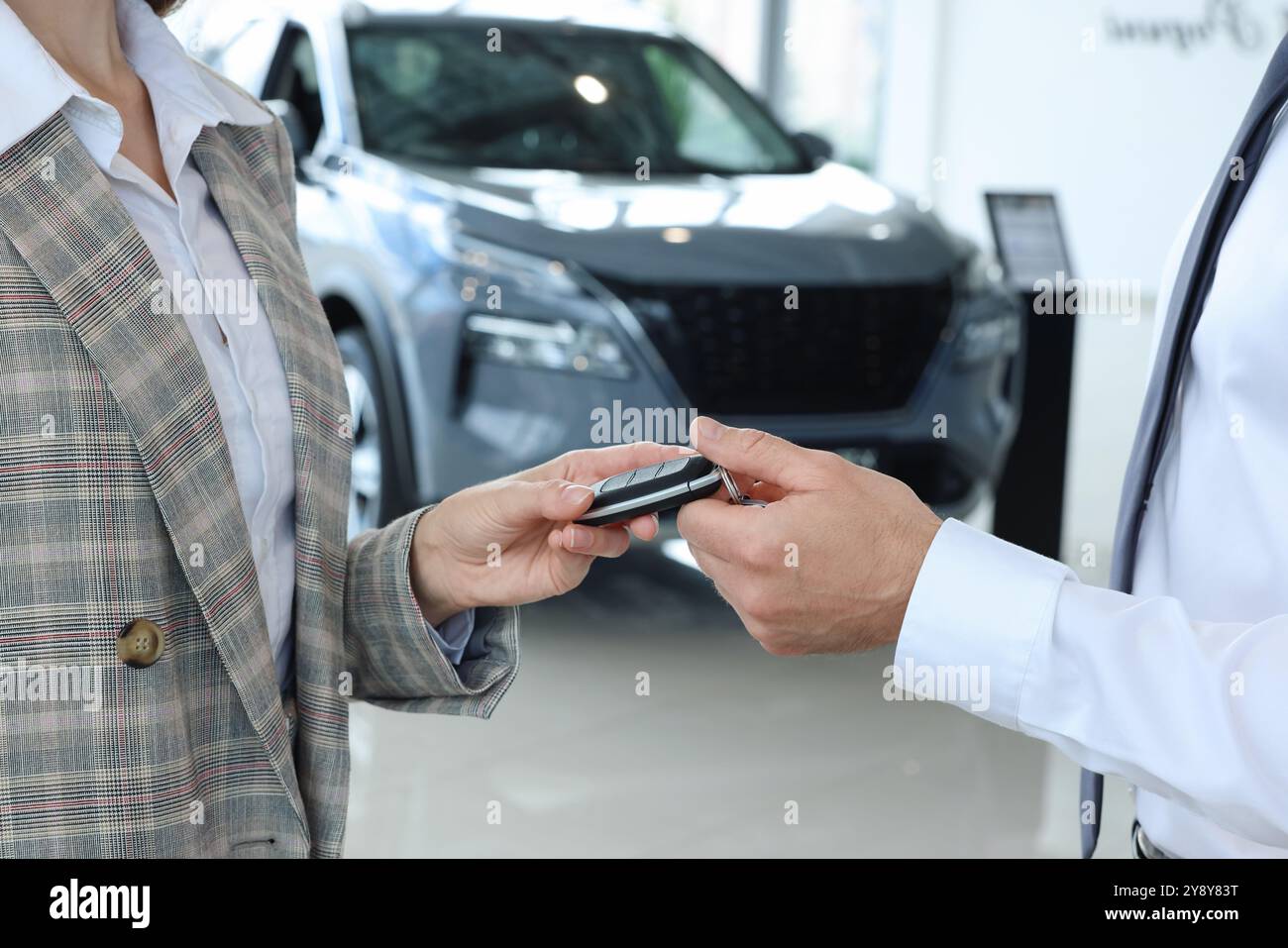 Saleswoman giving key to client near new car in salon, closeup Stock ...