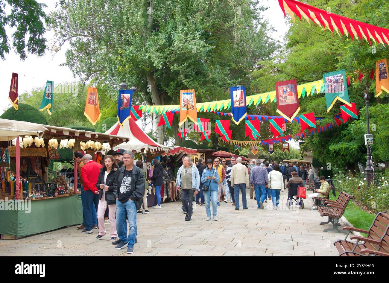 Fabric garlands and pennons across the street with tourist shoppers during the week of El Cid fiestas Paseo del Espolón Burgos Castile and León Spain Stock Photo