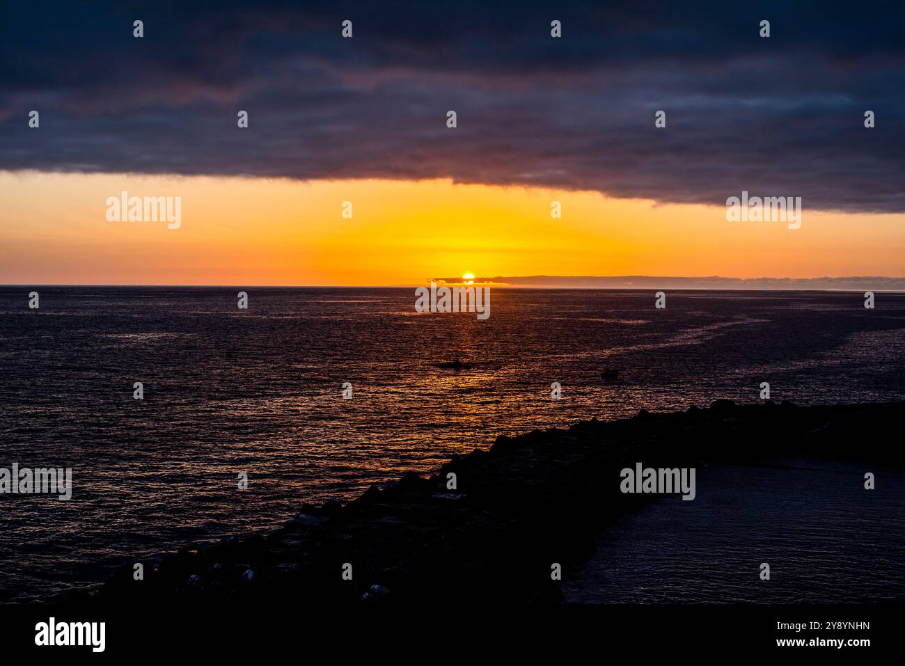 sunset over the atlantic ocean with the bay and the rocks , photographed from the rocks of the bay of Porto do Sol in Madeira Portugal Stock Photo