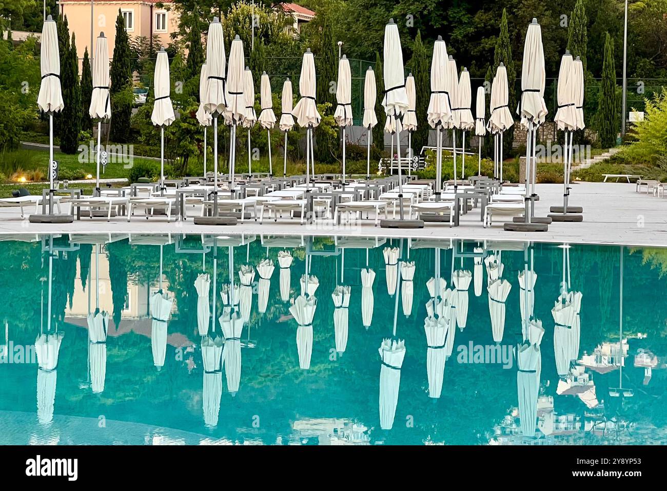Umberellas and sunbeams packed away for evening reflected in swimming pool. Sheraton hotel,Sebreno near Dubrovnik, Croatia - Smartphone Captured Stock Image