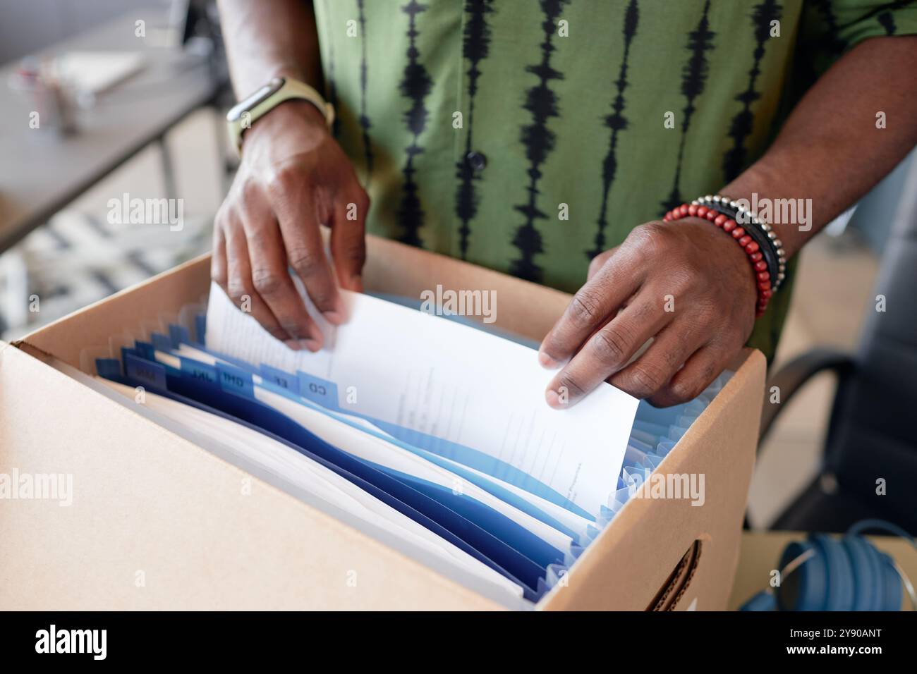 Close up of male hands sorting through documents in folder box while working in office, copy space  Stock Photo