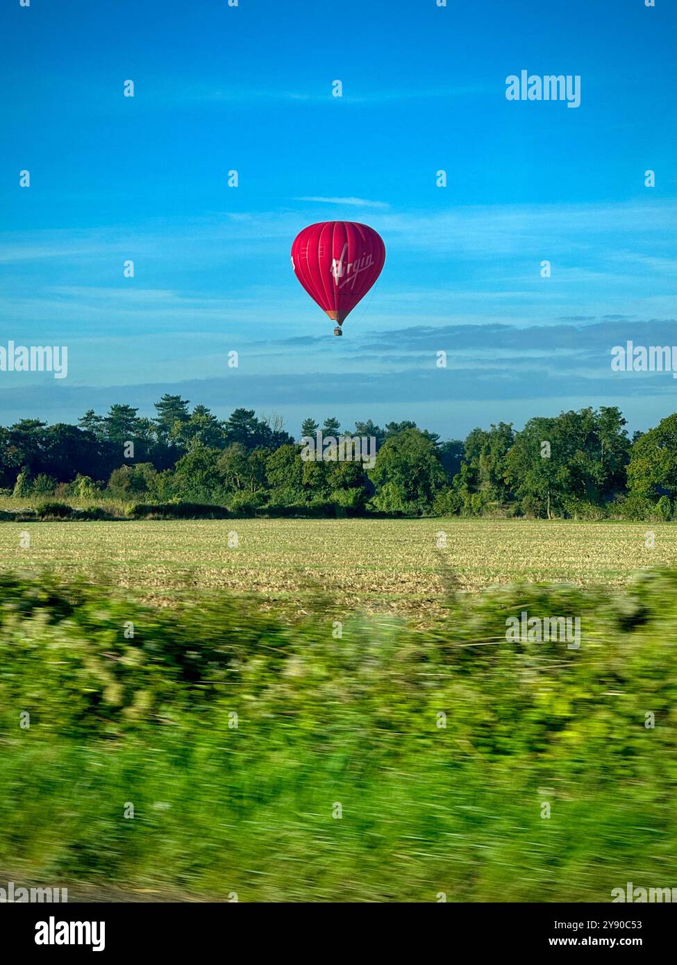 Red hot air balloon, floating low over green field. - Smartphone Captured Stock Image Red hot air balloon, floating low over green field. - Smartphone Captured Stock Image