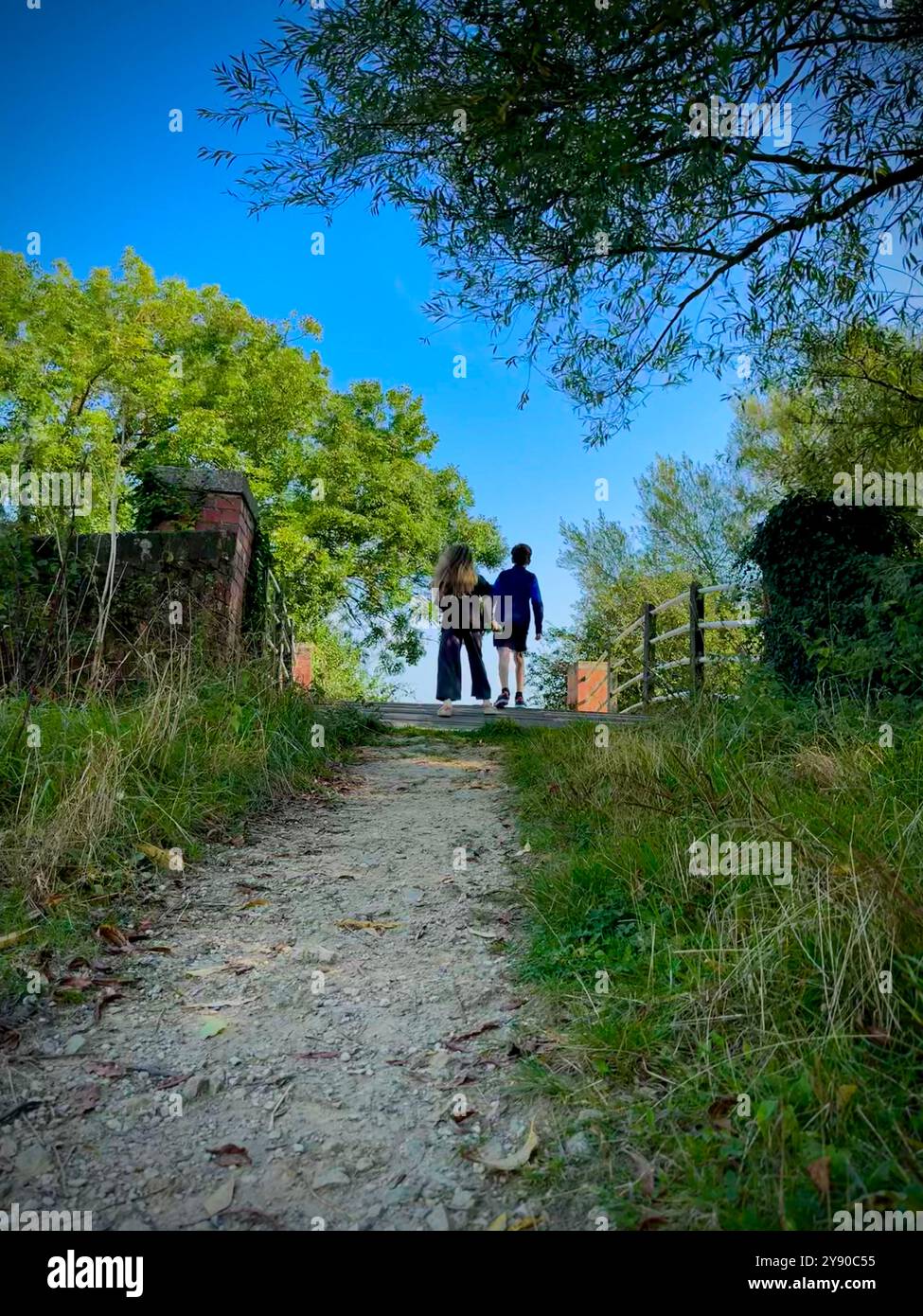 Family walking over canal bridge on summers day in rural countryside. - Smartphone Captured Stock Image