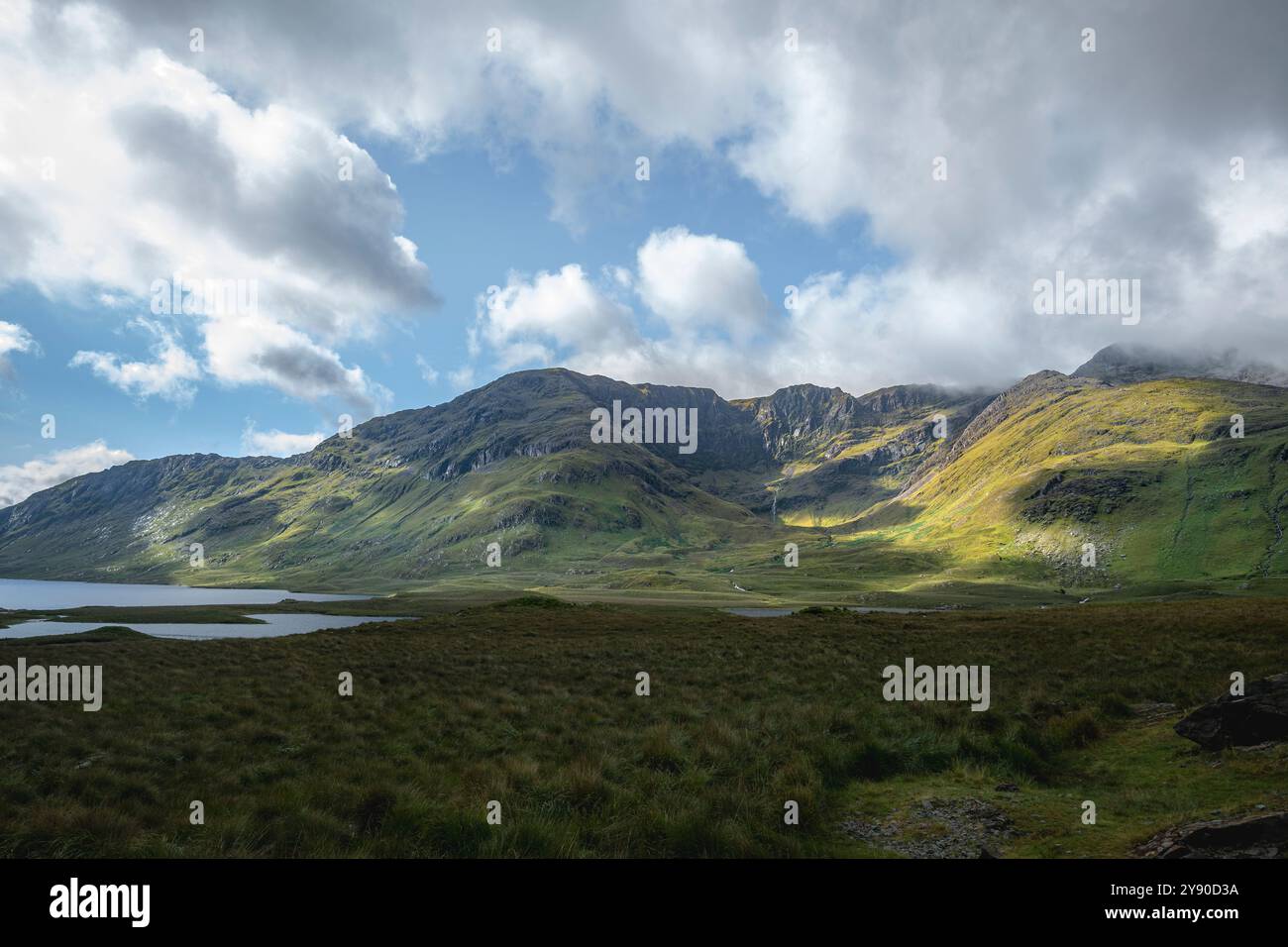 Play of light and shadow across the lush green grass of mountain Slopes at Doo Lough Valley, Glencullin Mountain, County Mayo, Ireland Stock Photo