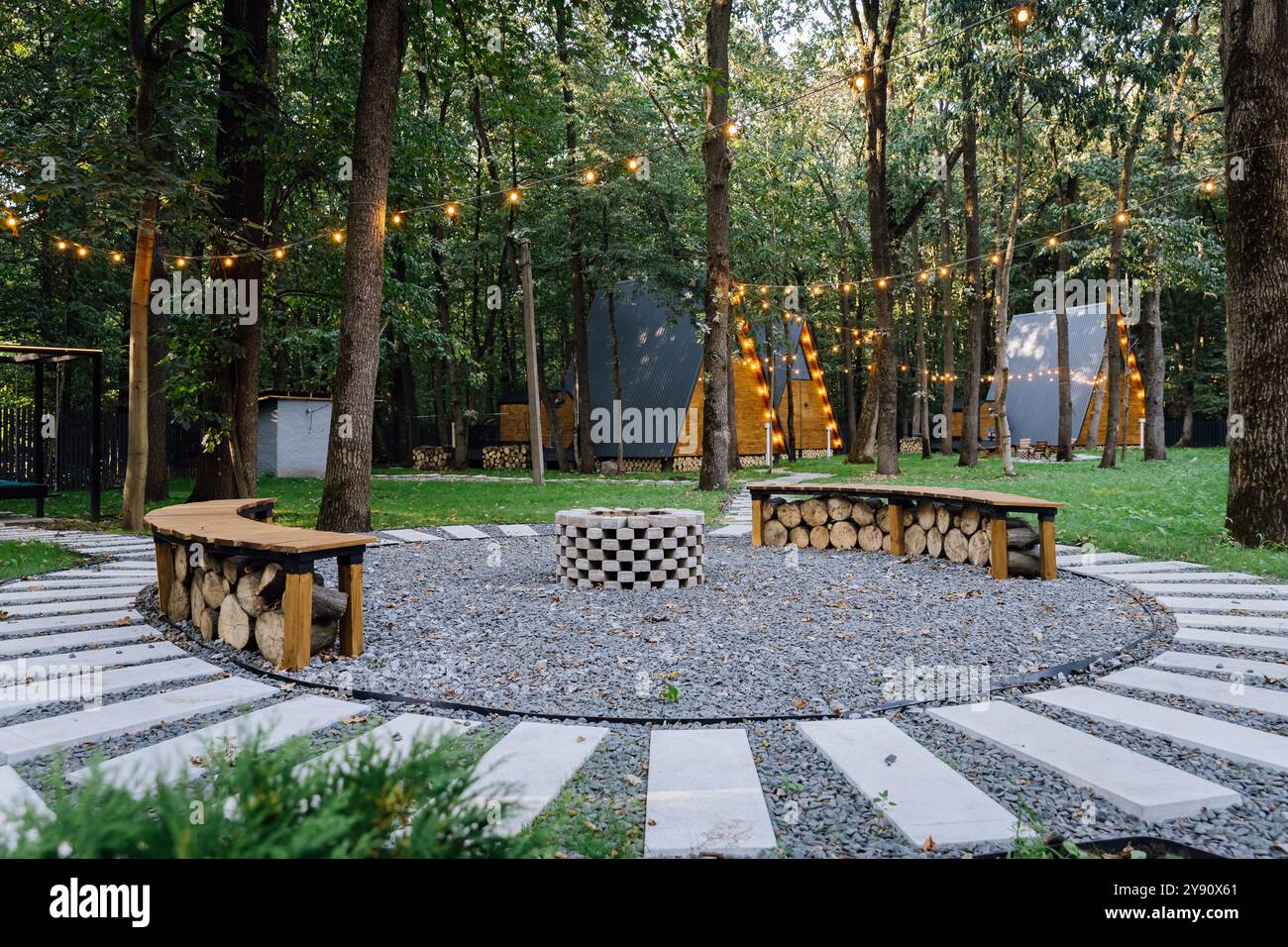 Cozy fire pit seating area in forest glamping with glowing string ...