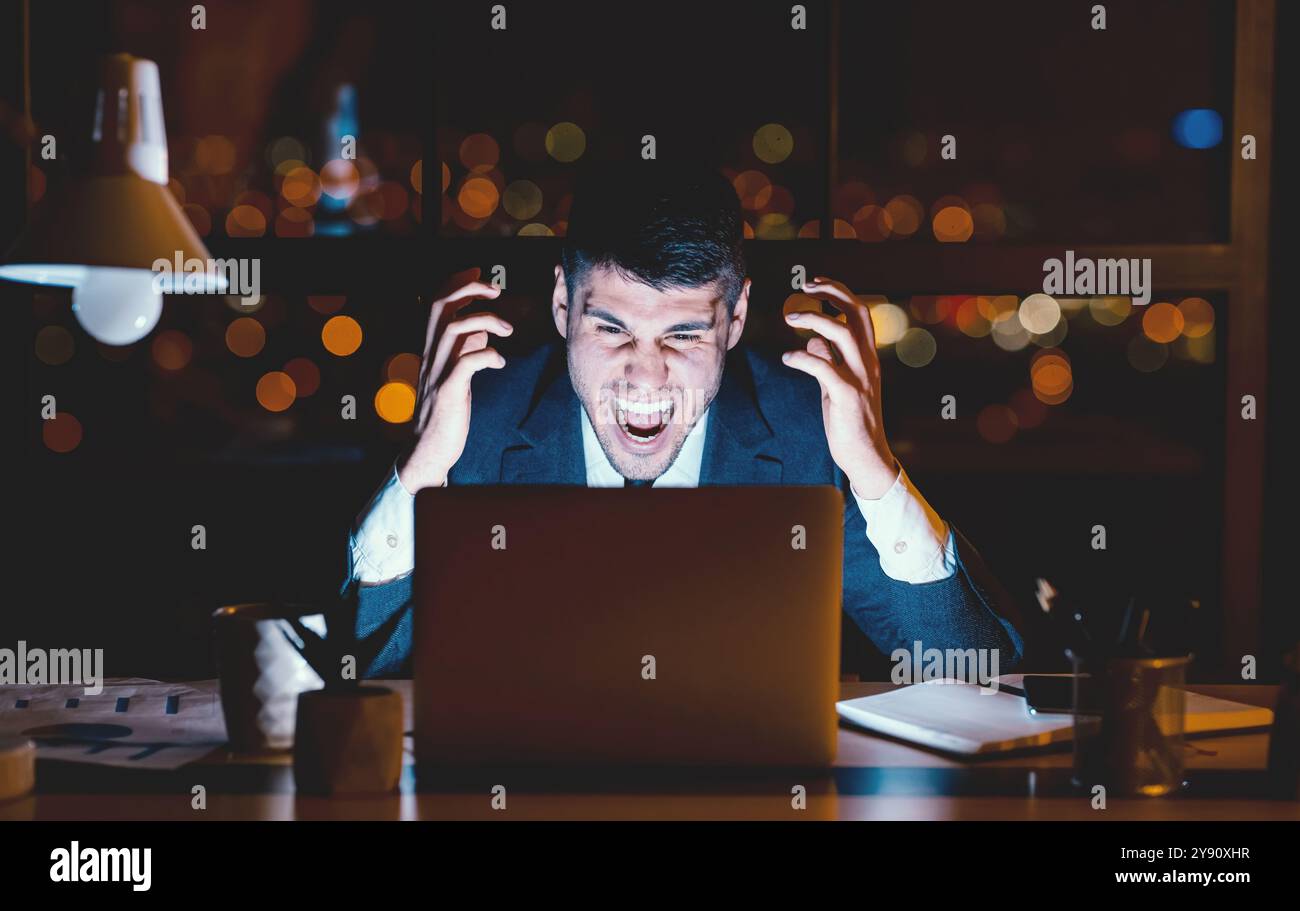 Mad Entrepreneur Shouting Angrily Working In Modern Office, Low Light Stock Photo