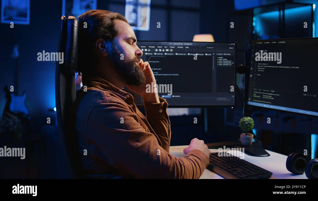 Annoyed software technician rubbing temples in frustration after ...