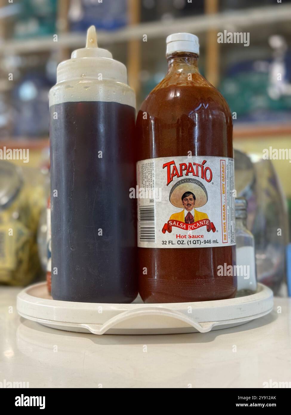 A large bottle of Tapatio Sauce beside a plastic jar of Maple Syrup at Dream Fluff Donuts in Berkeley, California. - Stock Image