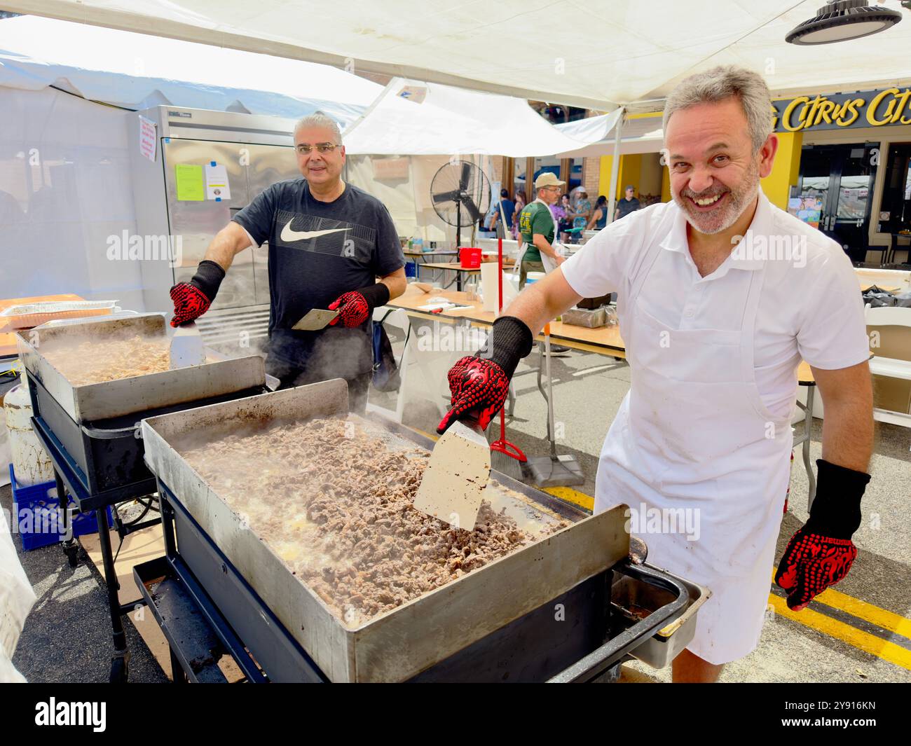Two smiling men cooking Lebanese food at the Orange International Street Fair in Orange, California, USA - Smartphone Captured Stock Image