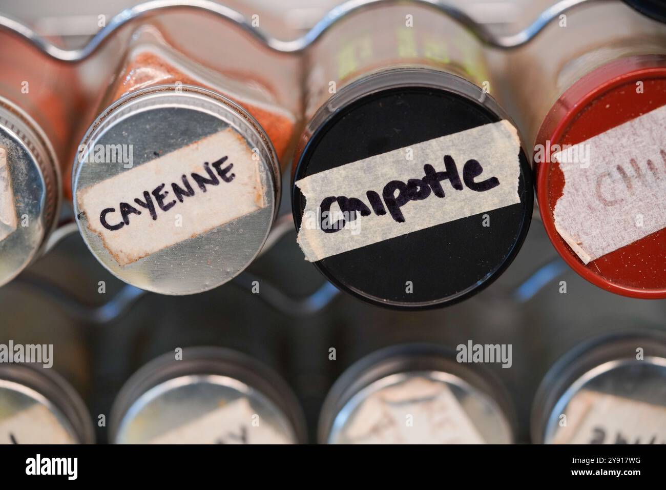 Cayenne and chipotle spice masking tape label on spice jar in spice rack. Stock Photo