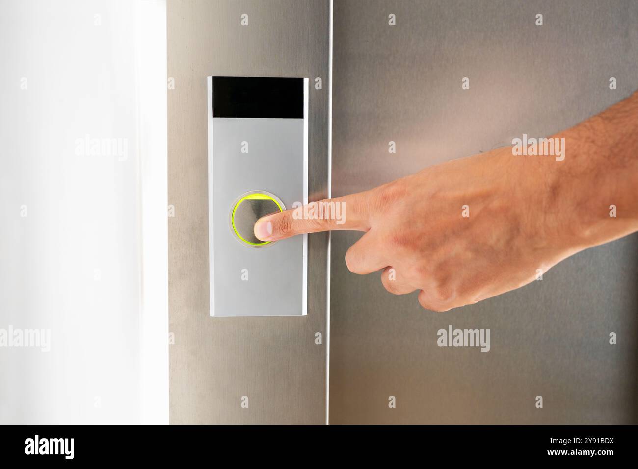 A man's finger presses the elevator button at building Stock Photo