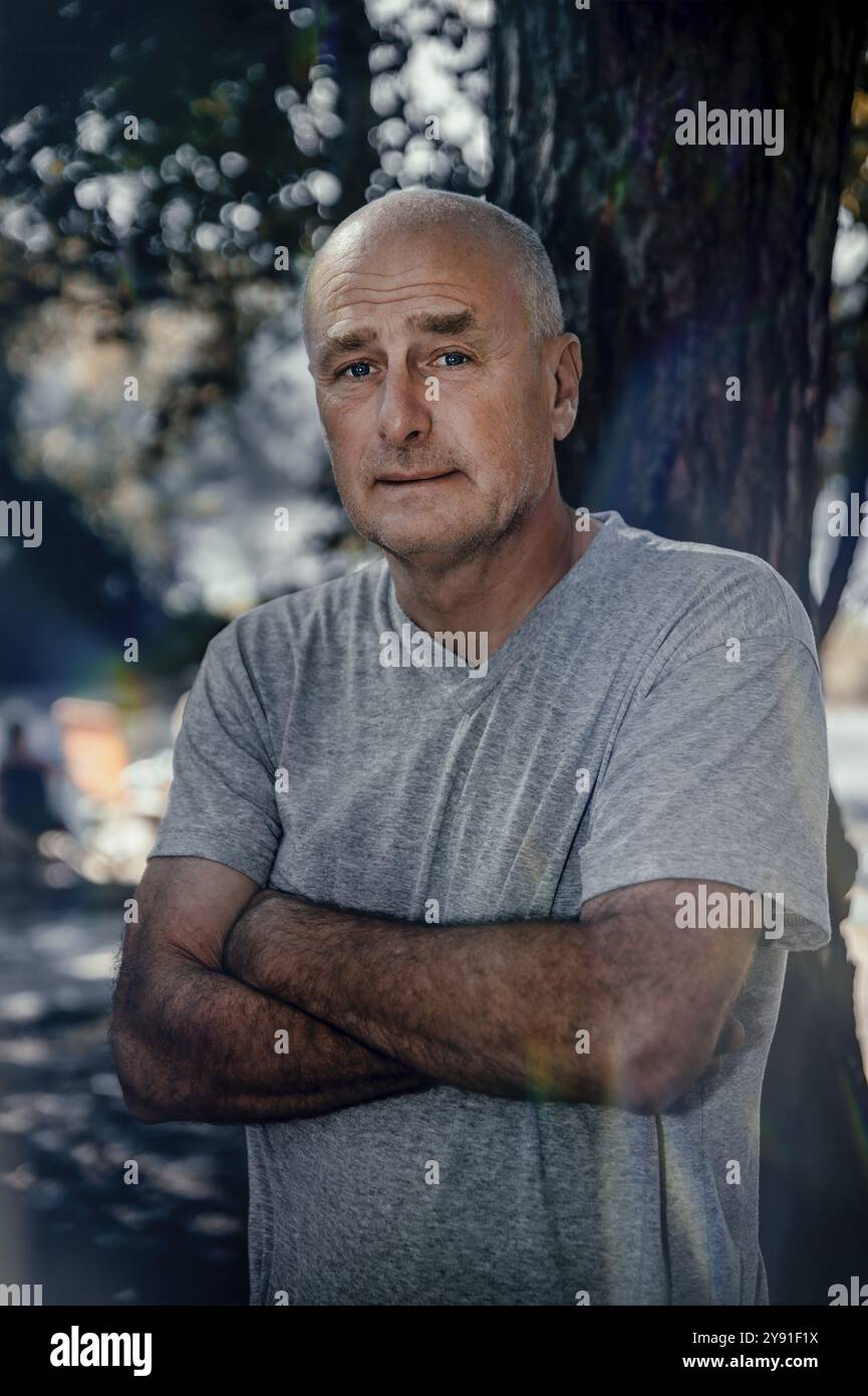 Half portrait, man, 50 plus, camera view, bald head, arms crossed, background blurred, edge of forest, Germany, Brandenburg, Storkow, public ground, E Stock Photo