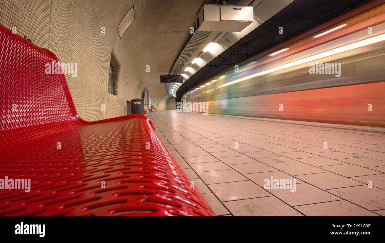 Modern underground railway track bed with red bench and passing train ...