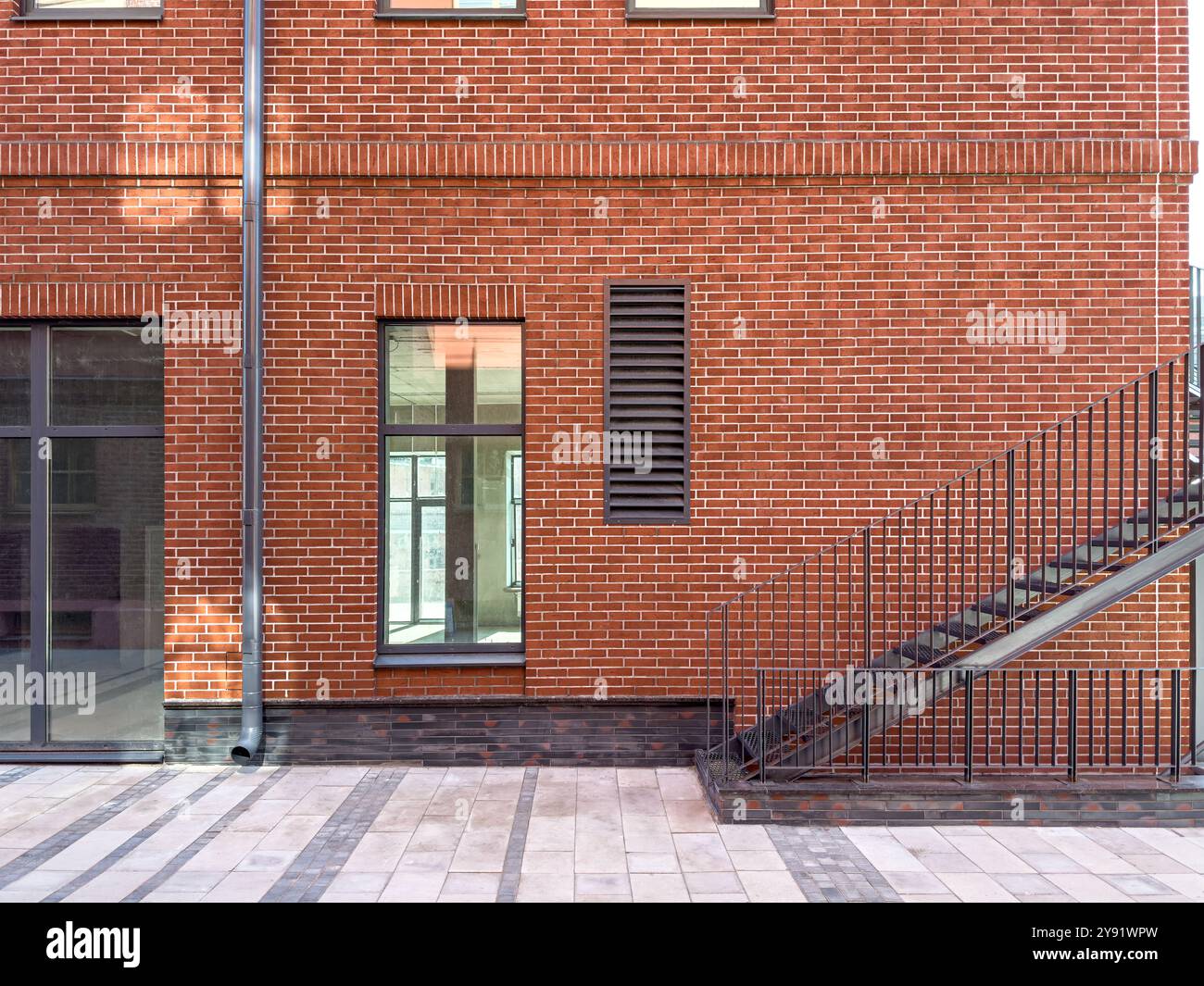 renovated old red brick industrial building. corner of building with outdoor metal stairs. Stock Photo