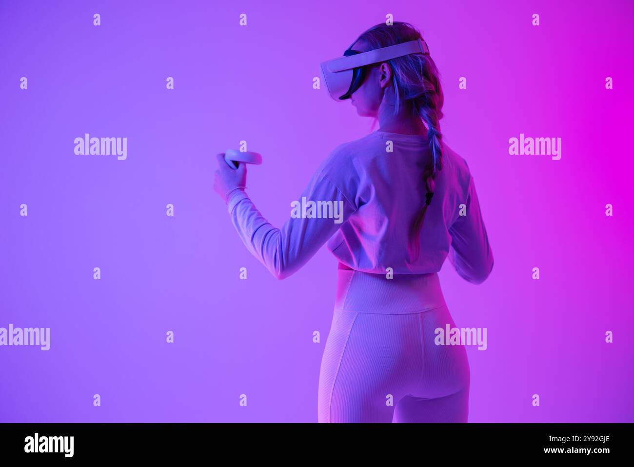 Woman experiencing virtual reality in vibrant neon purple lighting ...