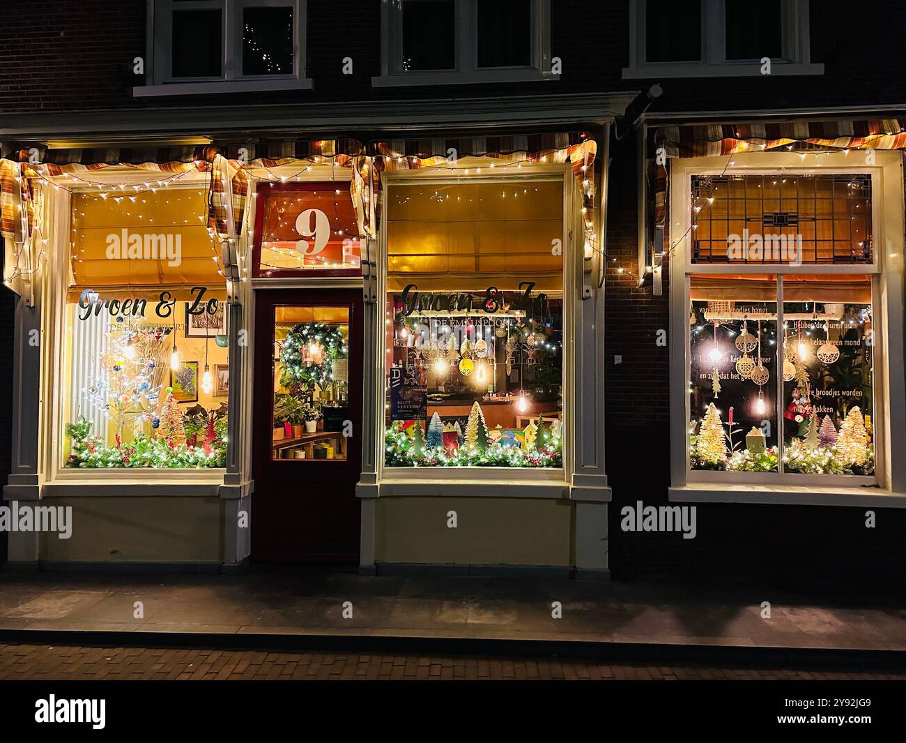 Delft, Netherlands: 17th December 2023; A plant shop in Delft called Groen and Zo which is illuminated at night with lights and Christmas decorations - Smartphone Captured Stock Image