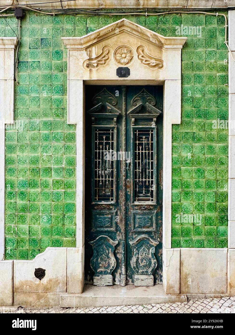 Old weathered green door surrounded by ceramic tiles in the Algarve, Portugal - Smartphone Captured Stock Image