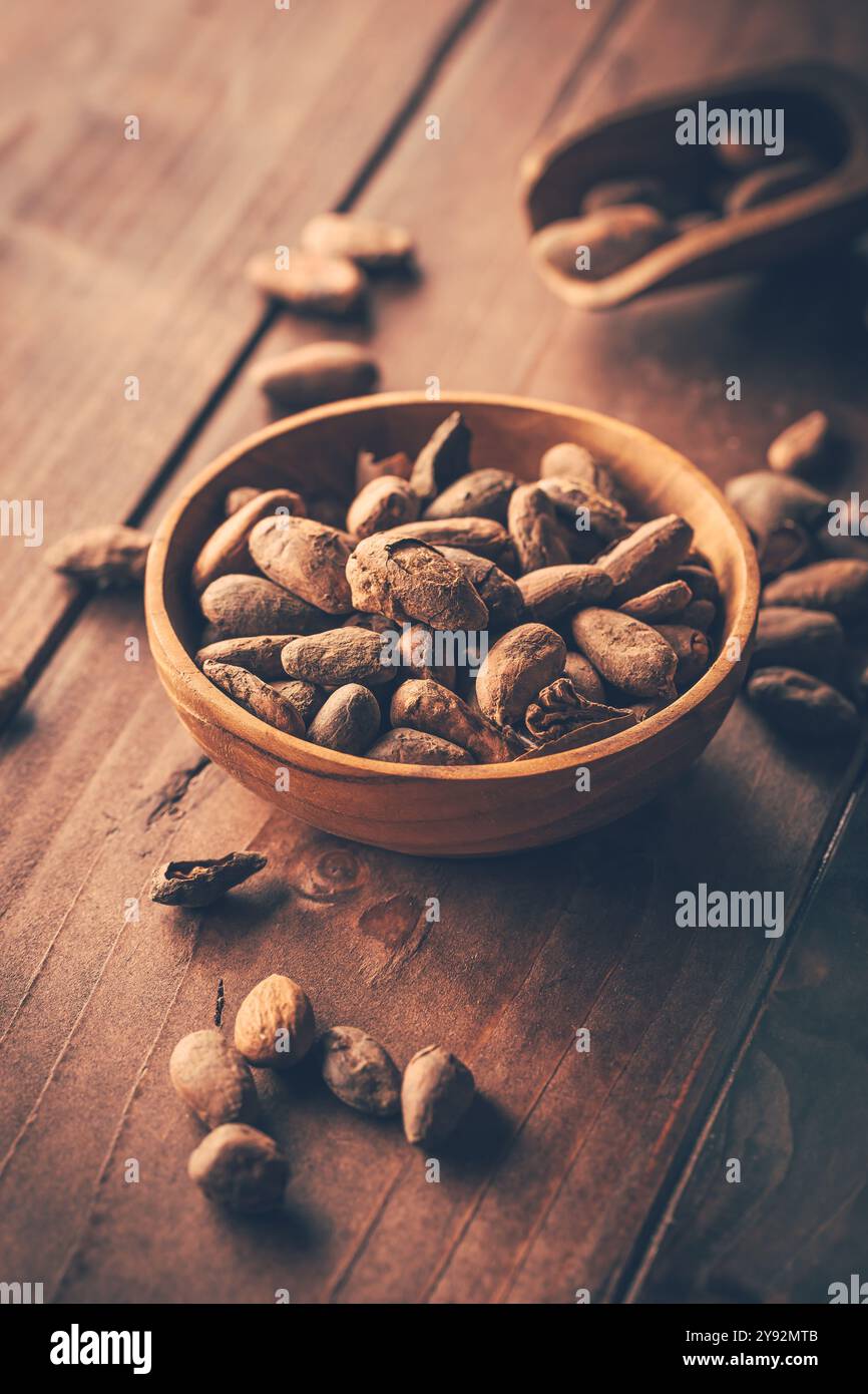 Organic cocoa beans in wooden bowl on wooden background Stock Photo