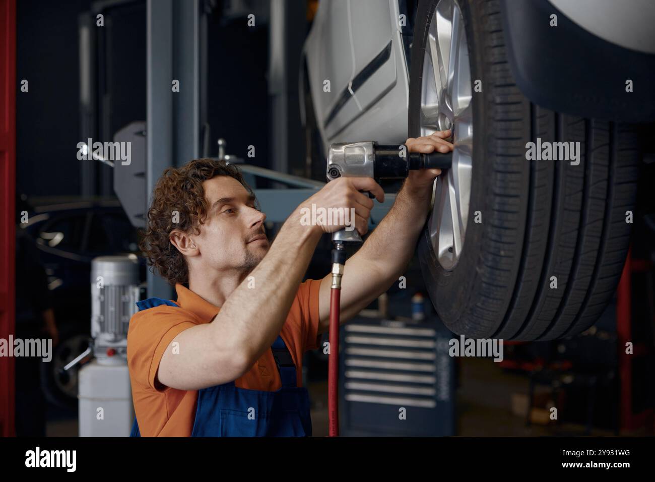 male-auto-mechanic-using-impact-wrench-during-tires-replacement-stock