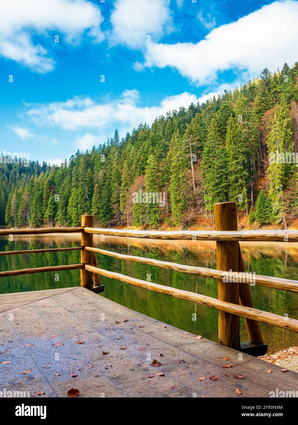 wooden pier on the lake synevyr in autumn. mountain landscape on a sunny day. scenery reflecting in the water. relax and leisure background Stock Photo