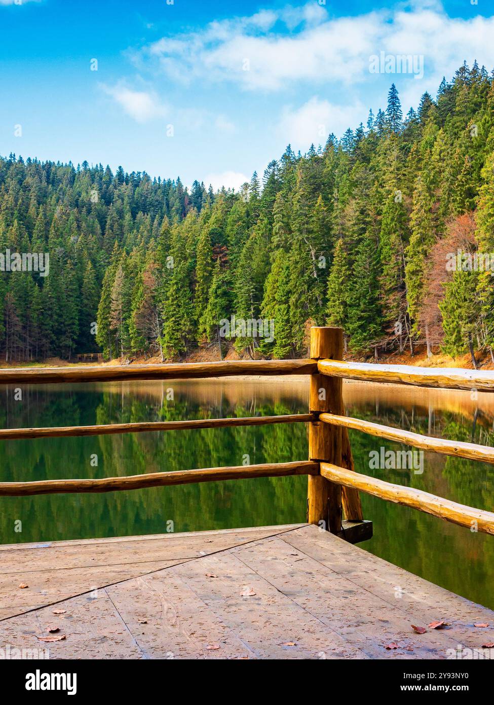 wooden pier on the lake synevyr in autumn. mountain landscape on a sunny day. scenery reflecting in the water. national park Stock Photo