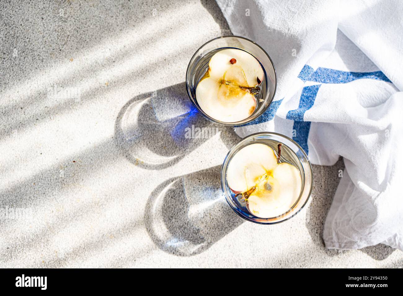 Top view of two glasses of apple water, made with pure water, organic apple vinegar, and fresh apple slices, beautifully illuminated by sunlight and r Stock Photo