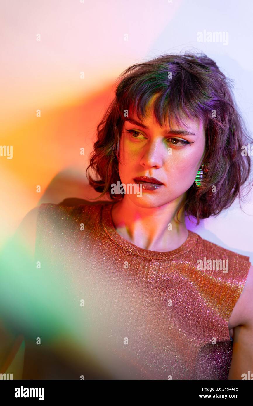 A portrait of a young woman highlighted by vibrant, colorful lighting ...