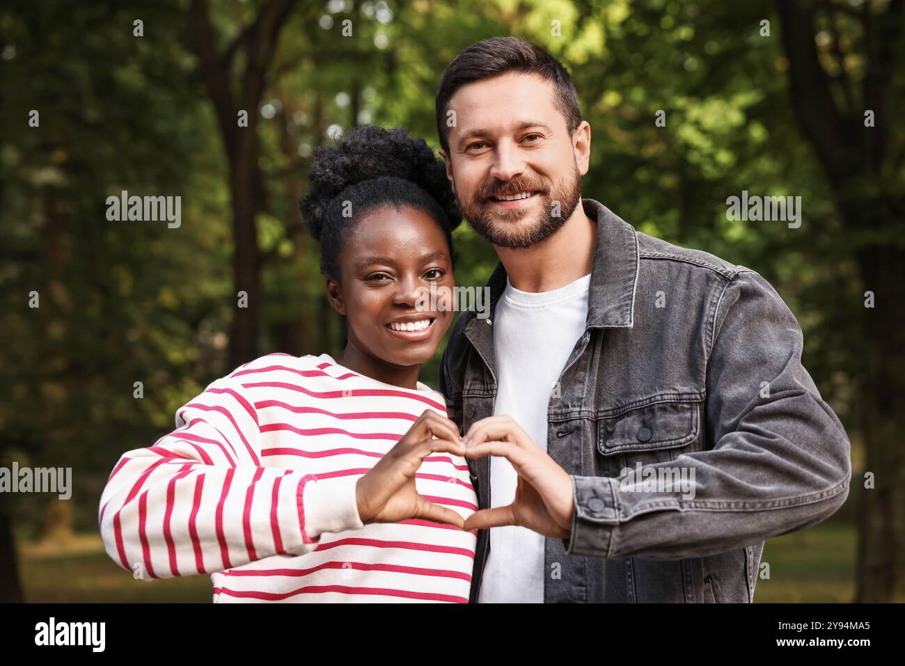 International relationships. Lovely couple making heart with hands outdoors Stock Photo