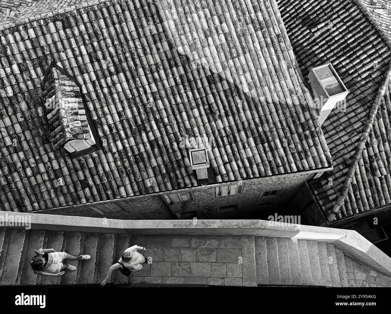 Looking down on tiled grooves of Dubrovnik old town from the city walls. Two people on steps of walls. Dubrovnik, Croatia - Smartphone Captured Stock Image