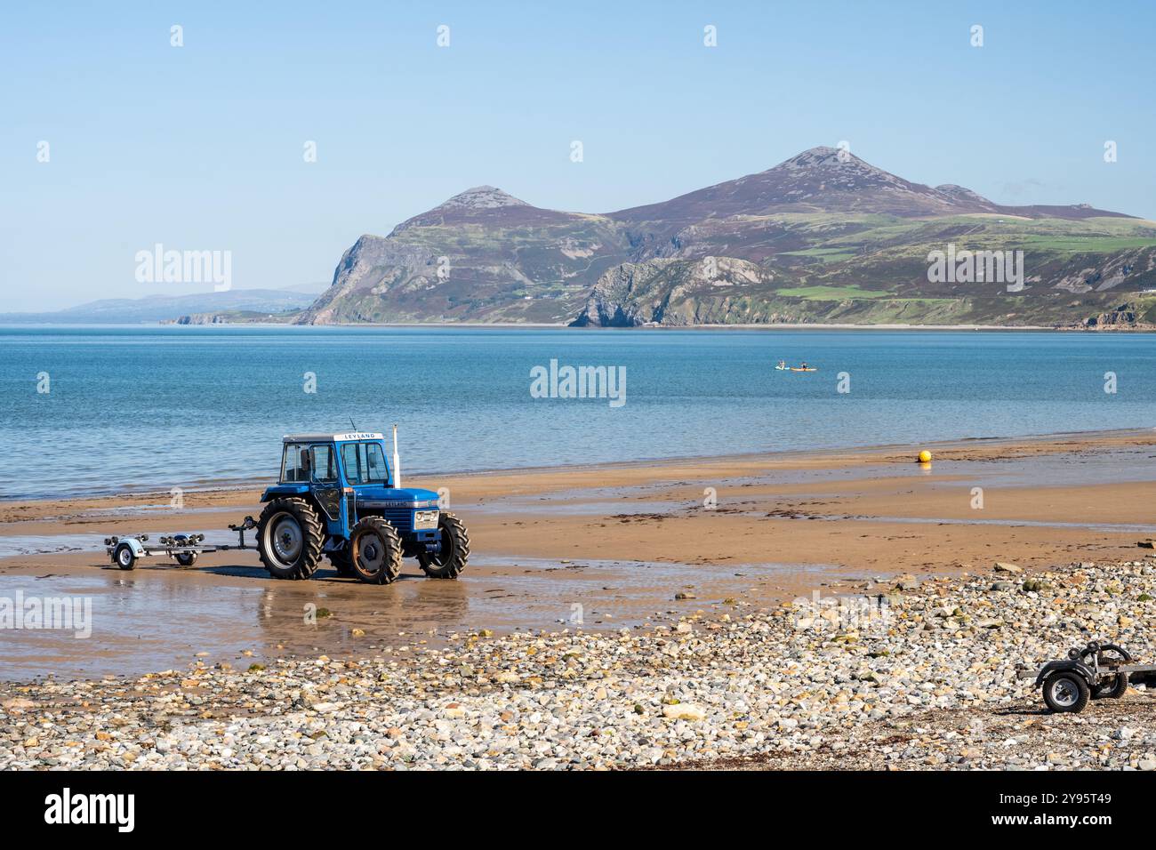 A tractor is parked on the beach at Morfa Nefyn on the Llŷn Peninsula of North Wales, with Yr Eifl hill rising in the distance. Stock Photo