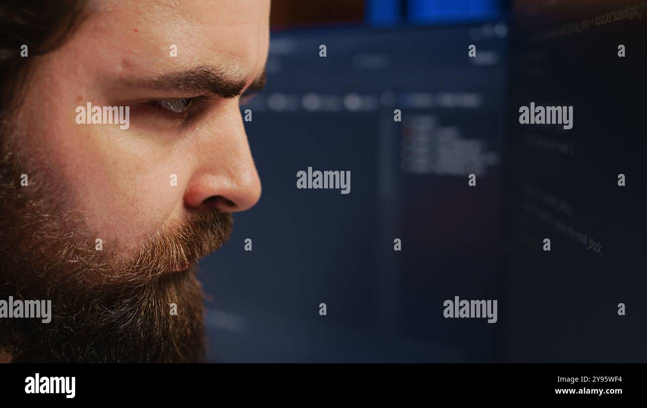 Software engineer concerned, concentrating on finding bugs while coding on computer, extreme close up. Troubled IT professional frowning while looking at screen, confused by script errors, camera B Stock Photo