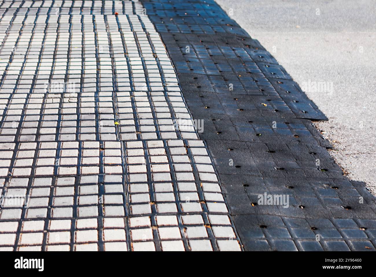 Paving black tiles on the ground in the city. Abstract street background.  Black and white tiled sidewalk featuring a geometric pattern Stock Photo