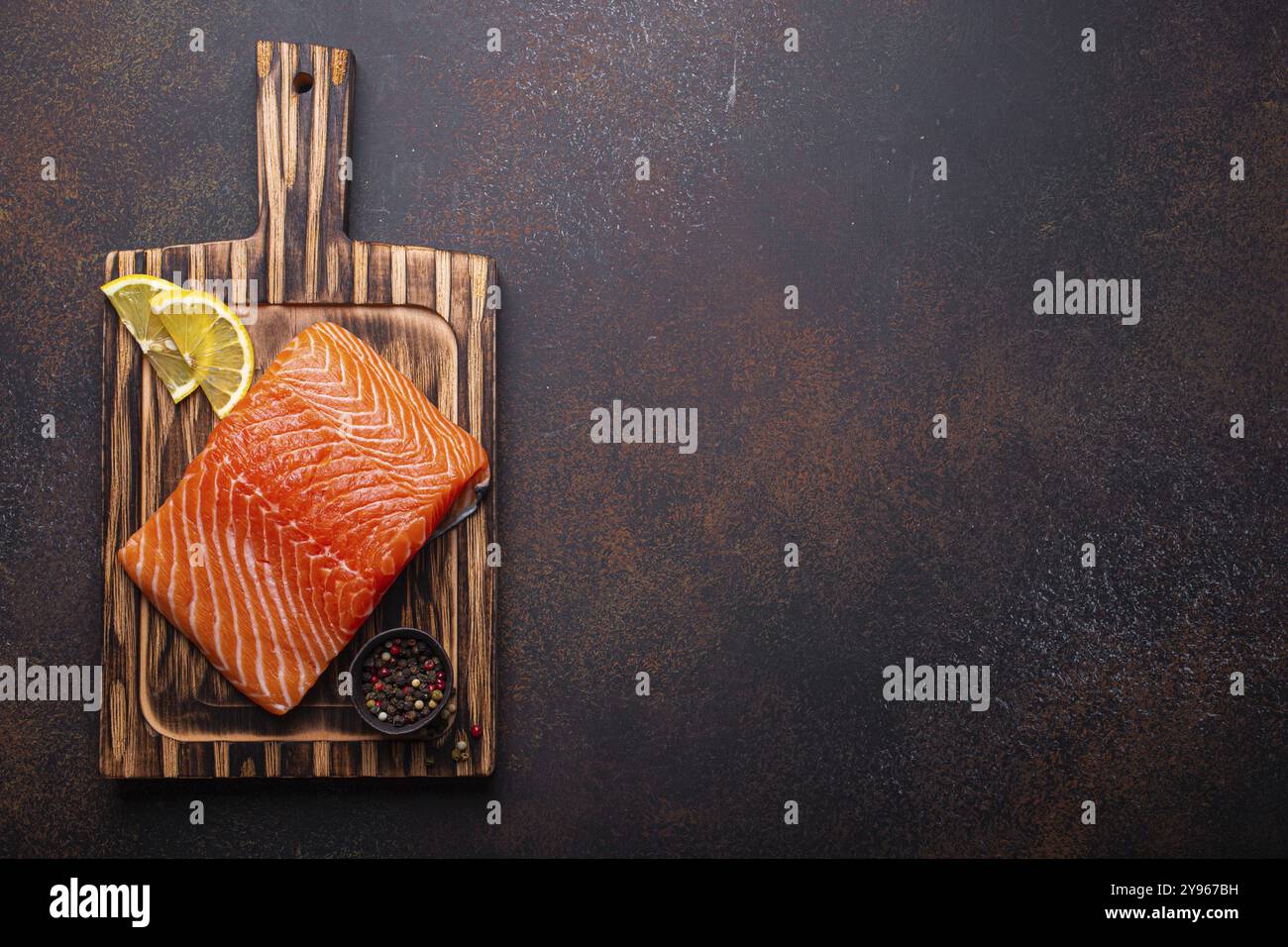 Fresh raw salmon fillet on wooden kitchen cutting board with seasonings ...