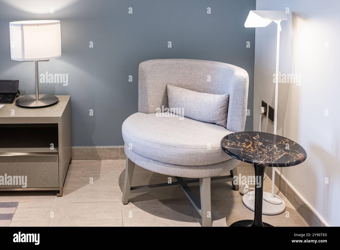 Minimalist living room interior design. Interior with grey wall beige armchair and marble side table of a hotel room. Stylish living room interior. No Stock Photo