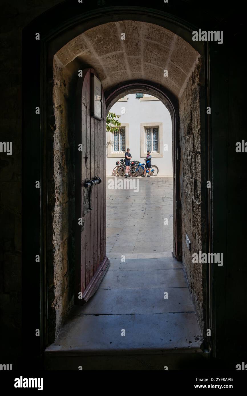 Two cyclists waiting to go on a ride, Church of Notre Dame, Saintes Maries de la Mer, Camargue, Bouches-du-Rhone, Provence, France. Stock Photo